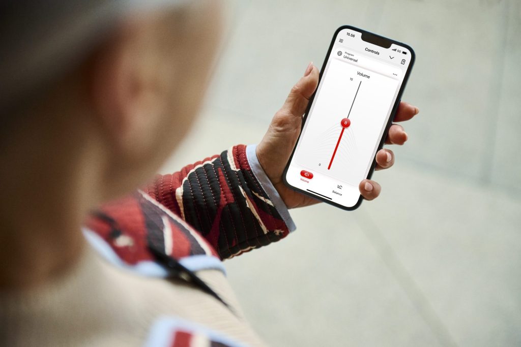 Person adjusting volume on hearing aid app