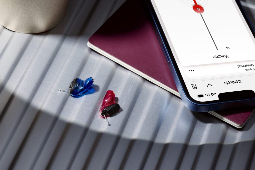 Red and blue hearing aids with smartphone