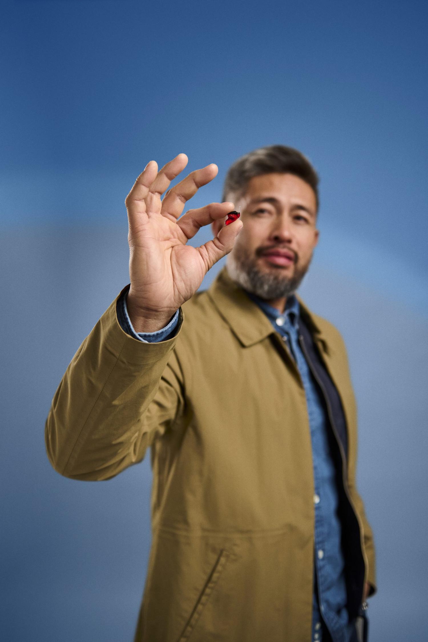 Man holding small red object up close