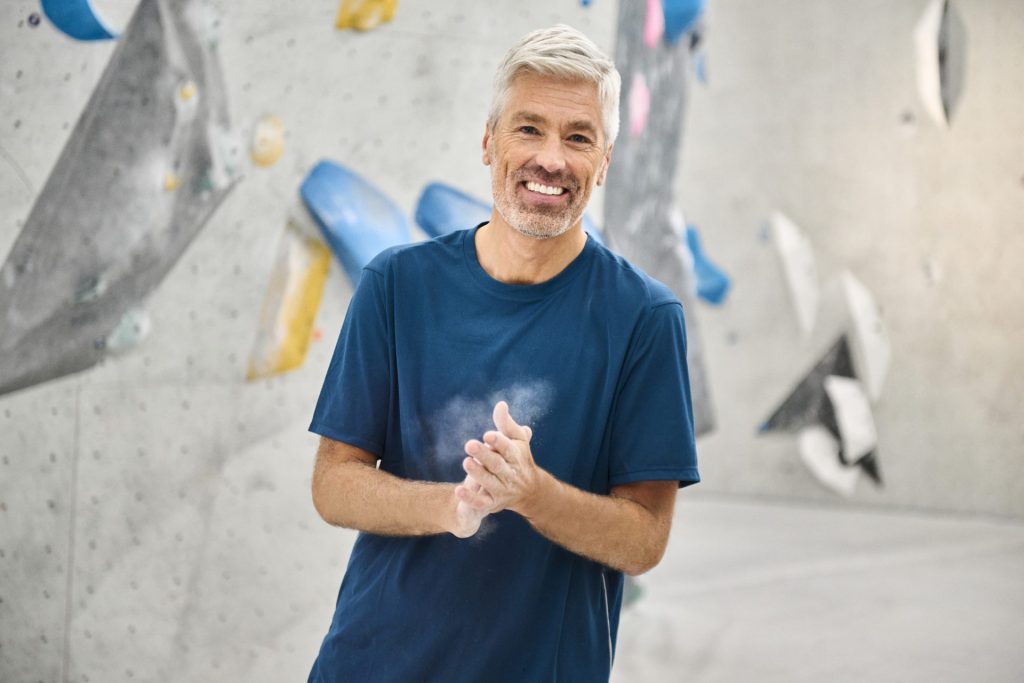 Man clapping in front of climbing wall