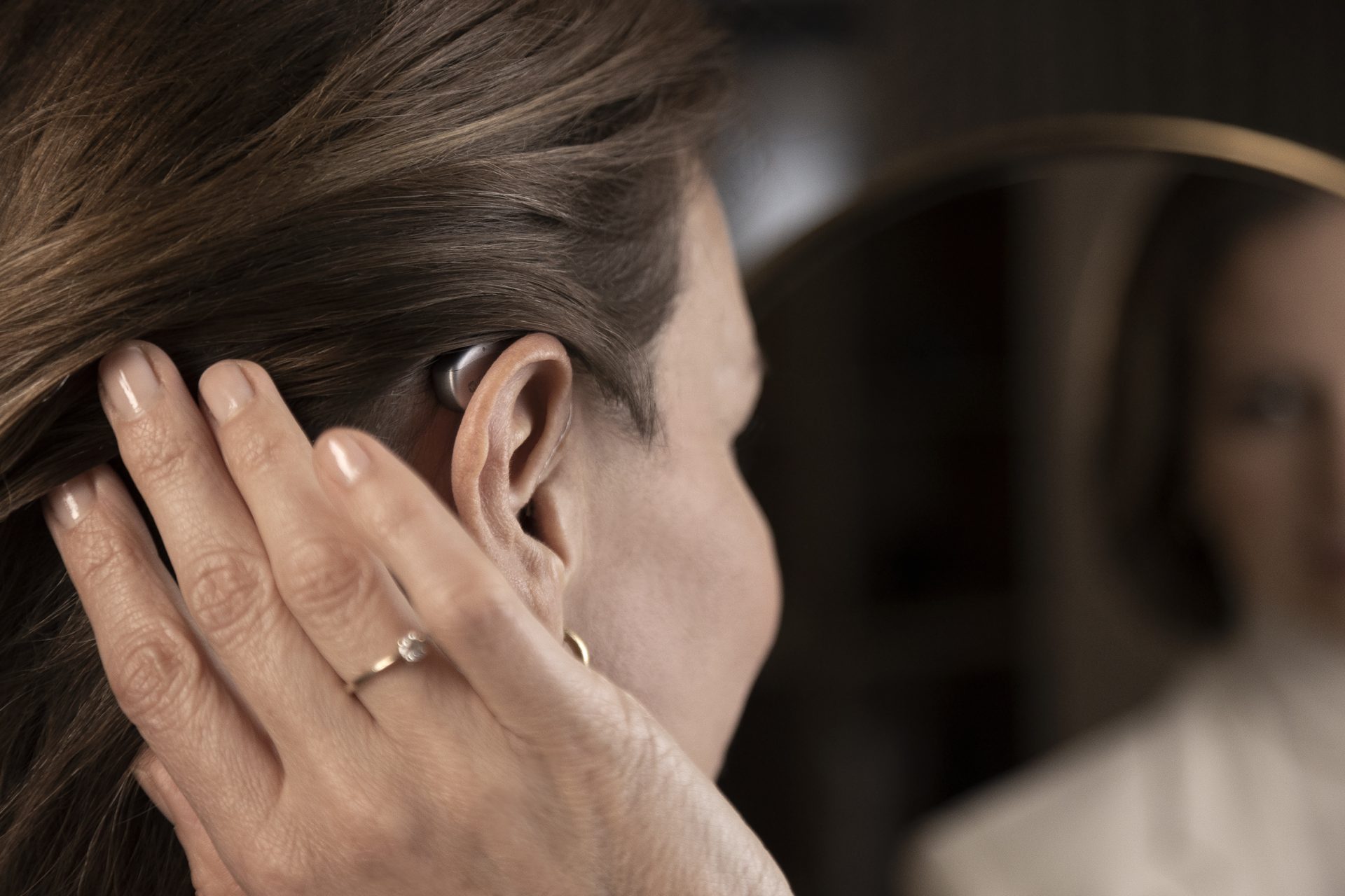 Woman adjusting hearing aid behind ear